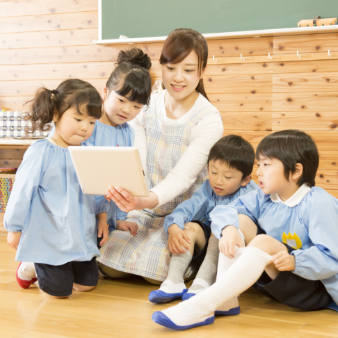 タブレットを持った先生と幼稚園児たち